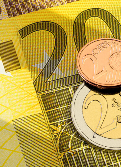 Verschiedene Euromünzen, ein Euro und ein Cent auf dem oberen Teil einer 200 gelben Euro-Banknote.